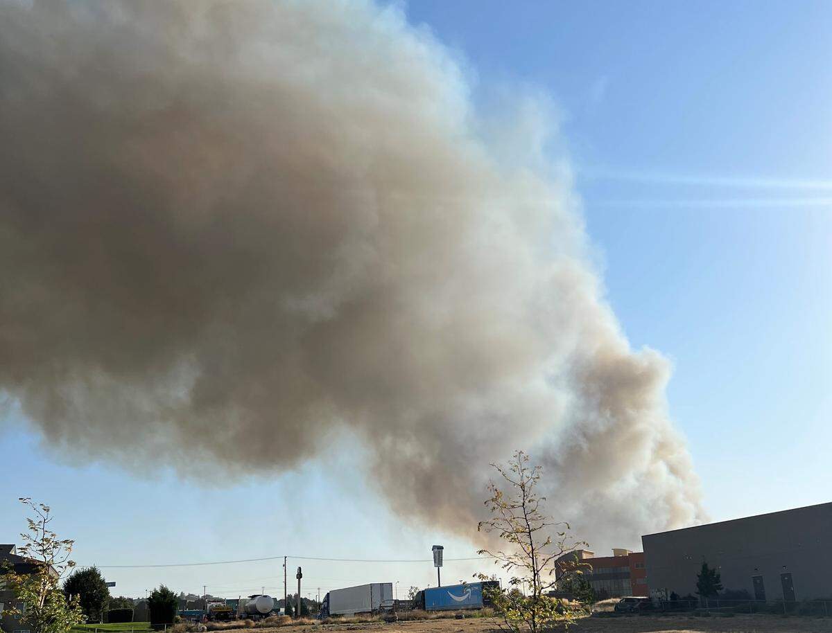 A plume of smoke from a fire near Southridge High School fills the sky in Kennewick, blocks away off of 24th Avenue on Thursday
