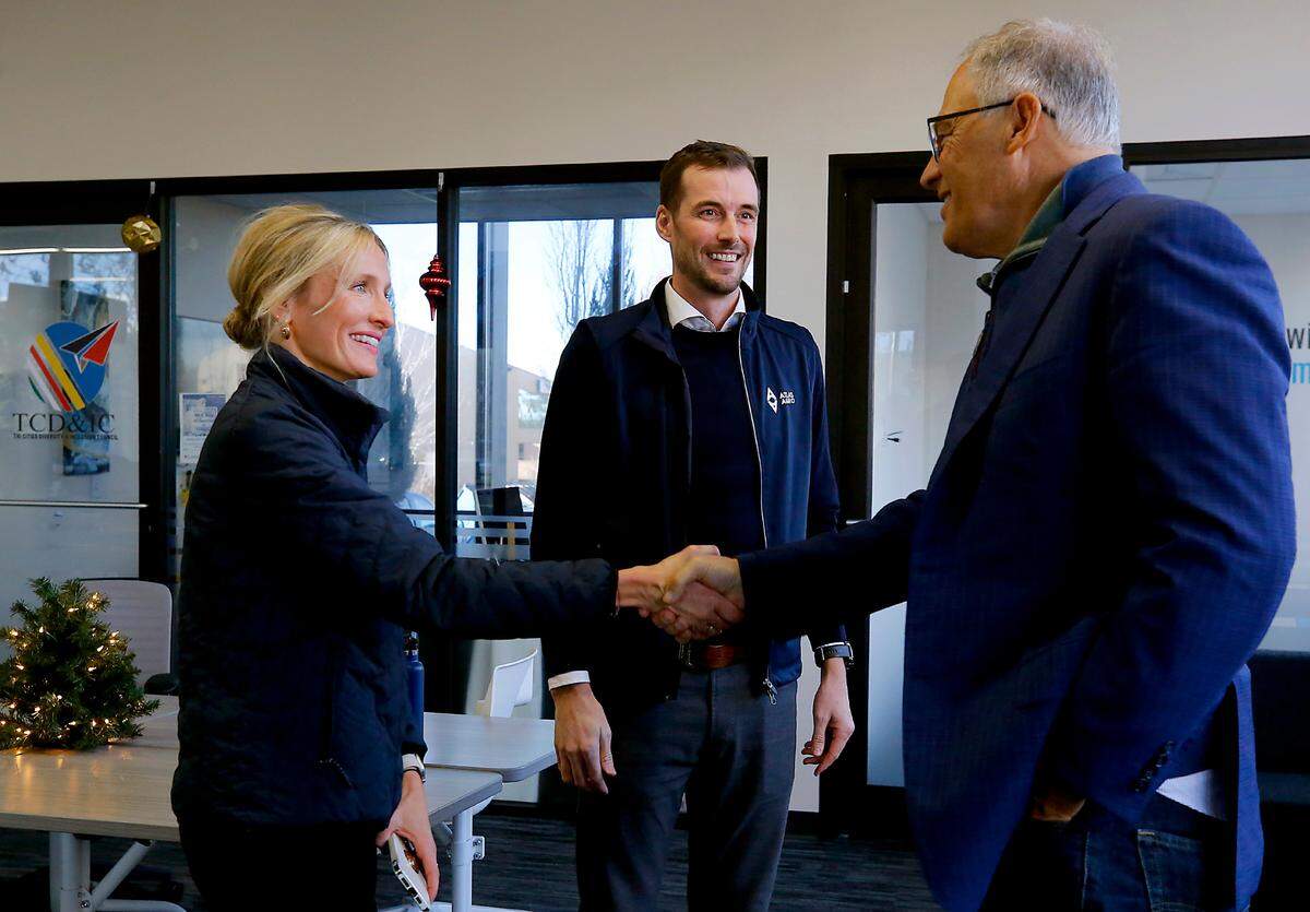 Gina Zejdlik, Atlas Agro director of policy and government relations, left and Dan Holmes, Atlas Agro North America executive director, middle, greet Gov. Jay Inslee last year in Richland.