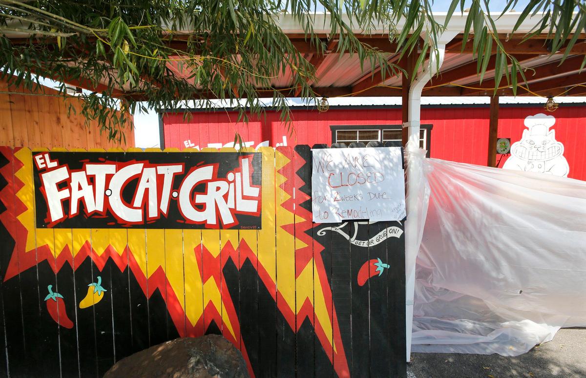 A section of painted fencing and plastic sheeting enclose the work area for the the installation of a larger El Fat Cat Grill during their remodeling project.