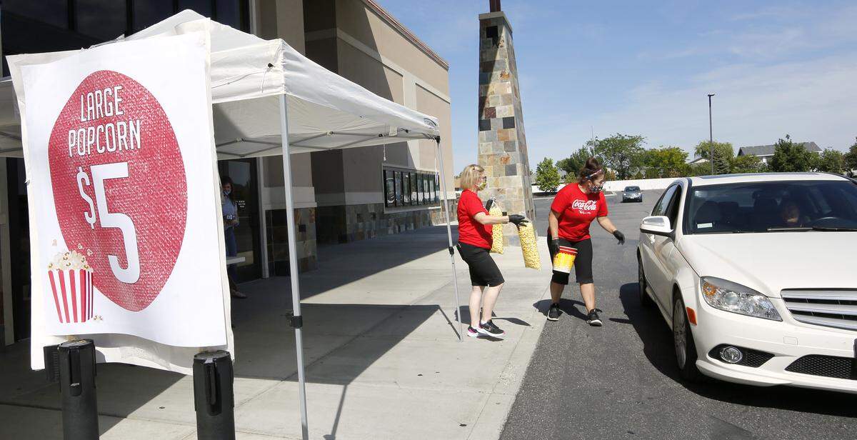 General manager Mamie Gale, left, and Marianne Bloxham deliver bags of popcorn to a customer in a car during a drive-thru sale of the movie time treat at Fairchild Cinemas location in Pasco during the coronavirus pandemic.
