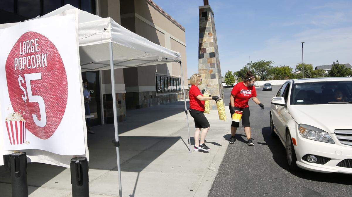 General manager Mamie Gale, left, and Marianne Bloxham deliver bags of popcorn to a customer in a car during last Friday’s drive-thru sale of the movie time treat at Fairchild Cinemas location in Pasco.