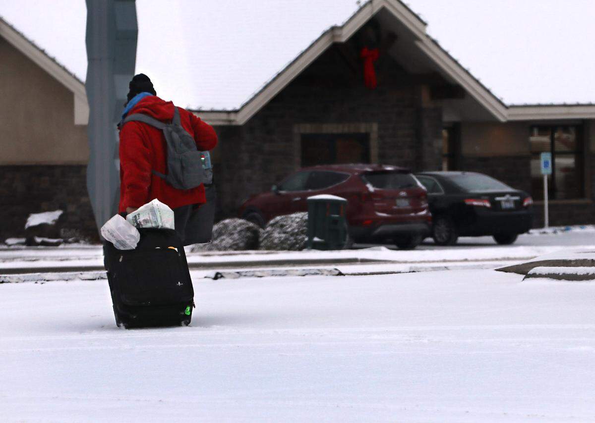 A possible homeless person trudges across a snow covered parking lot on West Clearwater Avenue in Kennewick following an overnight January snowfall.