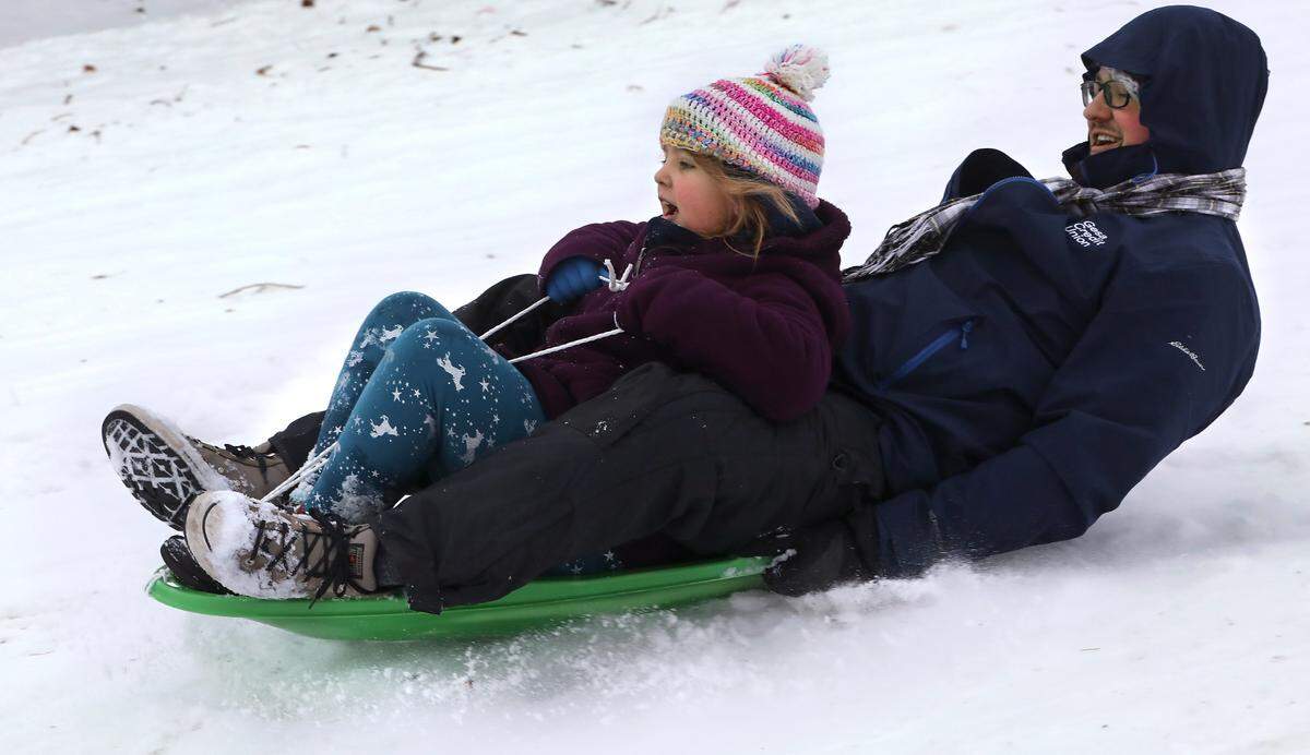 Mia Rex, 8, shares a sled ride with her father, Mikal Rex of Pasco, down the snow covered hill at Carmichael Middle School in Richland Friday morning after Tri-City school districts cancelled classes following winter storm that dropped about 4 inches of snow across the area creating hazardous driving conditions.