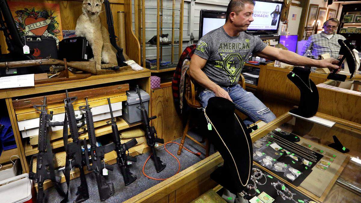 In this Oct. 20, 2017 file photo, Johnny’s Auction House owner John West prepares items, including a line of assault rifles at left, for auction where the company handles gun sales for both civilians and a half dozen police departments and the Lewis County Sheriff’s Office, in Rochester, Wash. The Spokane City Council has passed an ordinance prohibiting police from selling confiscated firearms, citing an Associated Press investigation that found that some guns sold by law enforcement were used in new crimes.