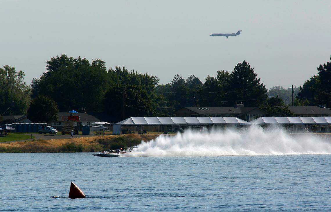 The vintage Miss Pay-N-Pak unlimited hydroplane takes a test lap on the Columbia River as a commercial airliner prepares to land in the Tri-Cities Airport in Pasco. Four of the vintage racing boats from a Seattle museum took part in the Tri-Cities Water Follies Columbia Cup racing event.