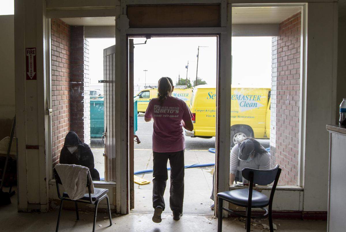 Employees from The Lodge at Columbia Point scrape paint at the entrance to Grace Kitchen, a Pasco nonprofit that plans to train impoverished women to be financially independent.