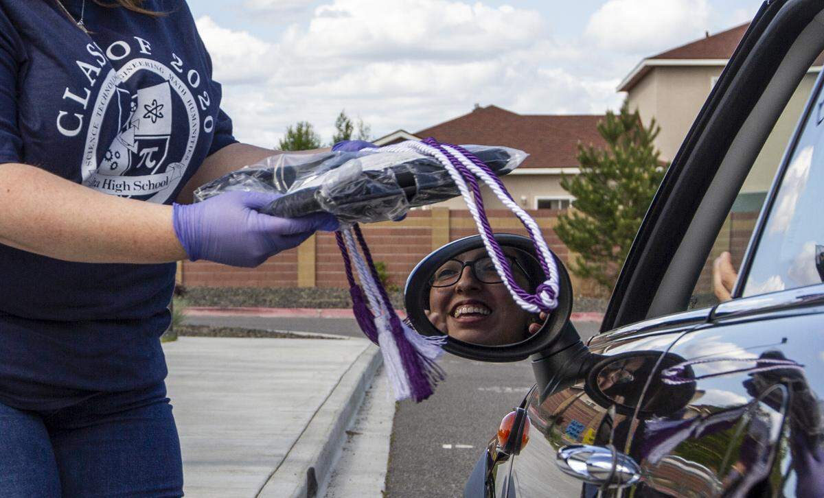 Seniors from Delta High School pick up their 2020 graduation caps and gowns at a drive-through event at the school’s campus in Pasco.