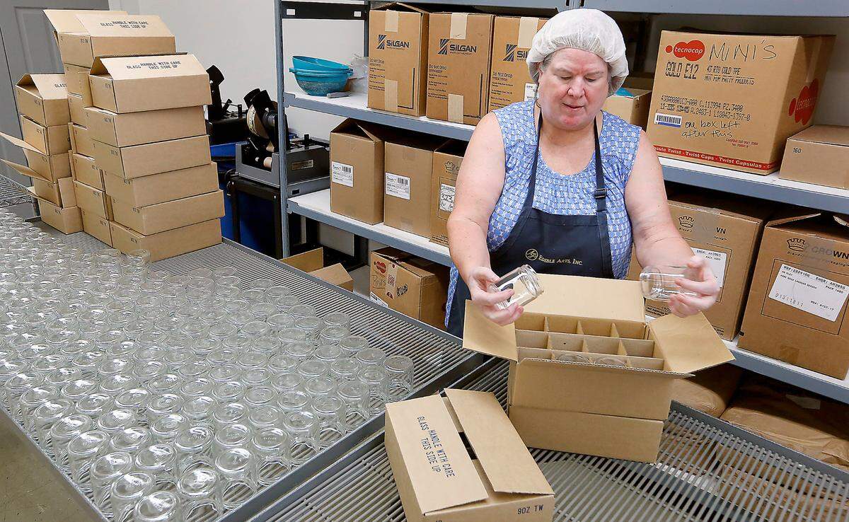 Juli Massingale of AJ’s Edible Arts unpacks empty glass jars at the company’s Pasco facility where they’ve been located more than 30 years.
