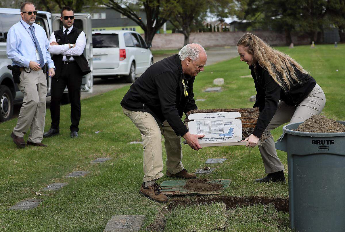 Benton County Coroner Bill Leach, left and Deputy Coroner Nicole Lee lift the fragile wood casket with Baby Doe after it was exhumed Tuesday at the Resthaven Cemetery in Richland..