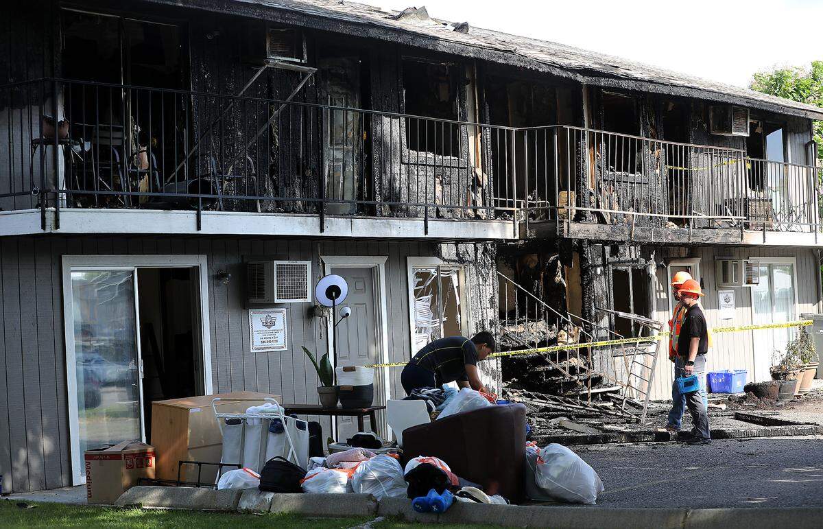 A ground-level resident removes belongings from the aprtment building at 1011 N. Cleveland St. in Kennewick after an early morning blaze heavily damaged the four-unit building.