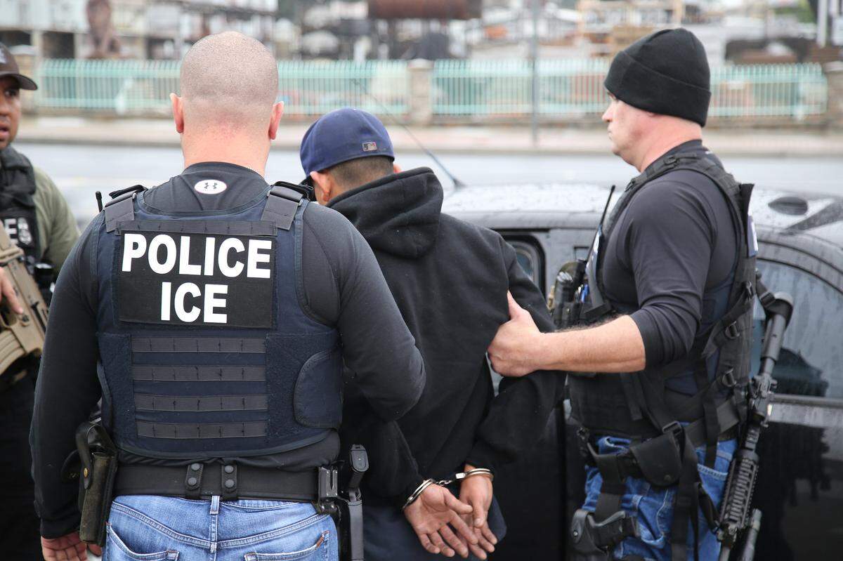 Immigration and Customs Enforcement officers detain a man.