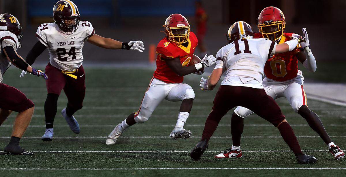 Kamiakin running back Makram Altahir (4) cuts away from defenders behind the block by his teammate David Kuku during their game against the Moses Lake Mavericks at Lampson Stadium in Kennewick.