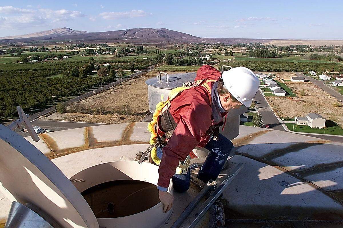 Herald photos/ André Ranieri Above: Benton City Mayor Lynn Johnson climbs onto the top of the towns new 750,000­gallon water tower Monday during a tour of the construction. The tower, built at a cost of $1.2 million, should be finished by December. Right: After spending about 10 minutes on top of the tower, Johnson begins his climb down about 200 rungs to terra firma.