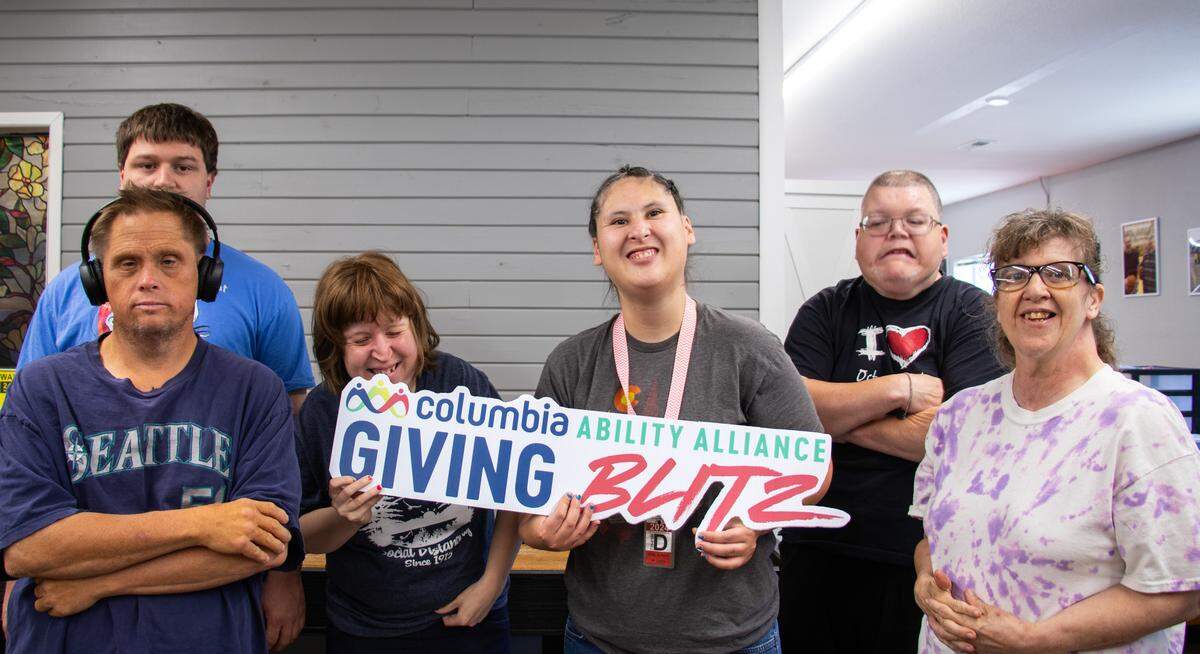 From left to right: David Sullivan (front row), Sergio Furniss (back row), Kendra Allen, Delena Potter, Kelly Morris, and Dawn Hunter hold a sign as they gear up for Columbia Ability Alliance’s 2025 Giving Blitz.