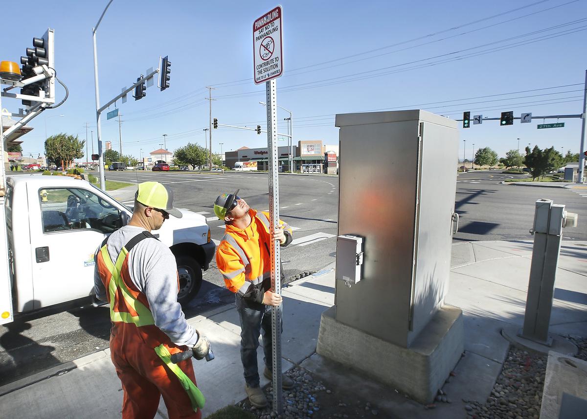 Kennewick employees Tyrel Davis, left, and Bryan Garza install one of 26 new signs Tuesday at the intersection of South Quillan Street and West 27th Avenue. The Kennewick Police Department is encouraging motorists to contribute to local charities instead of panhandlers. Watch a video at: tricityherald.com/video