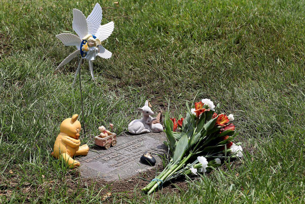 Decorations from Judi Nelson and flowers from Benton County Coroner employees decorate the restored gravesite of Baby Doe moments after Thursday's reinterment ceremony at Richland’s Resthaven Cemetery.