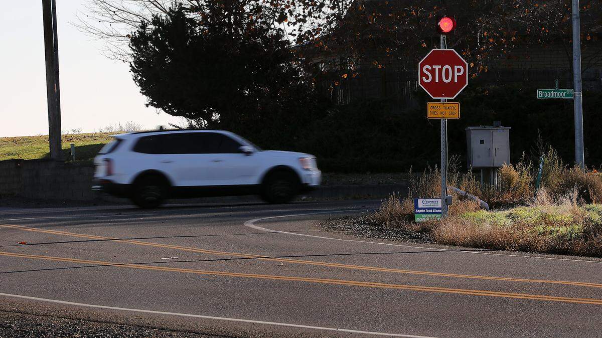 A vehicle on Broadmoor Boulevard passes through the intersection of Dent Road in Pasco the day following a serious collision at the intersection. Traffic on Dent Road is controlled a stop sign with a flashing light and warning sign the cross traffic does not stop.