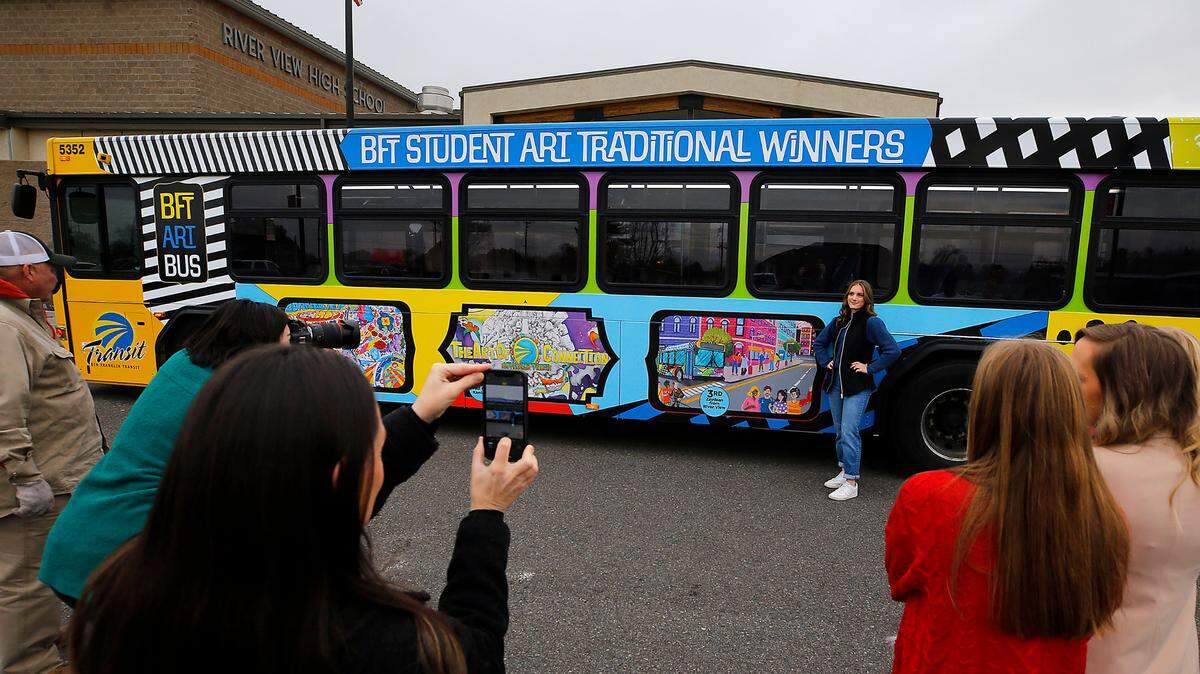 For the second time in three years, River View High senior Zaydean Valdez stands next to her winning artwork displayed on the side of a Ben Franklin Transit bus parked at the school in Finley.