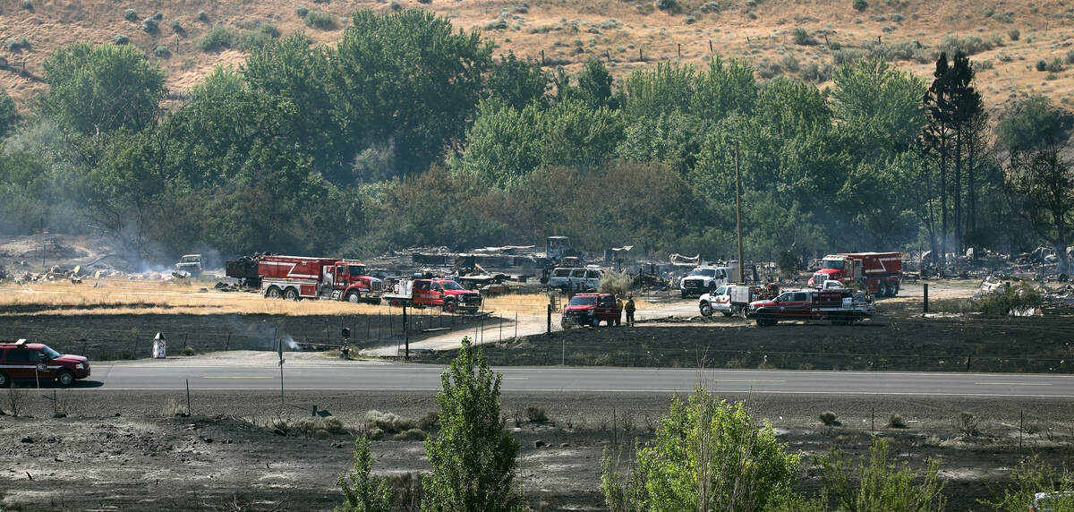A large number of firefighters and fire trucks work Monday to extinguish hot spots at 61901 Old Inland Empire Highway where fire officials say a house was consumed by Sunday's 800-acre wildfire.