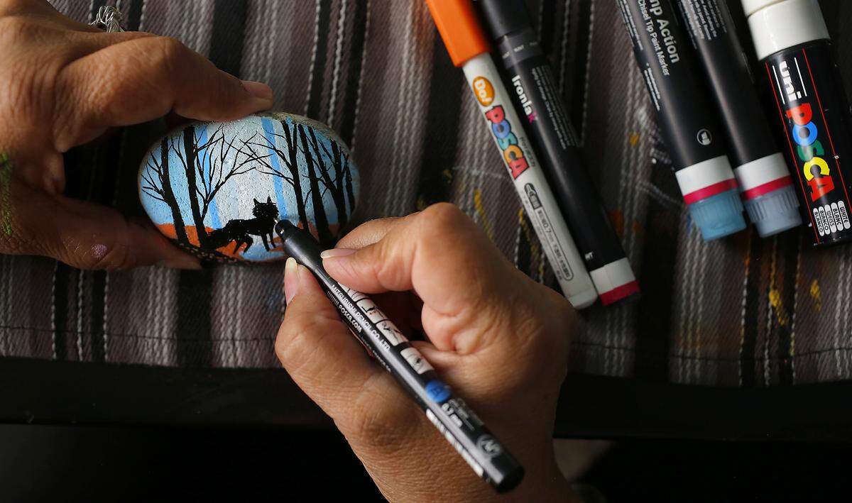 Lynnette Gallegos uses paint pens at her dining room table in her Kennewick home to work on her creations.