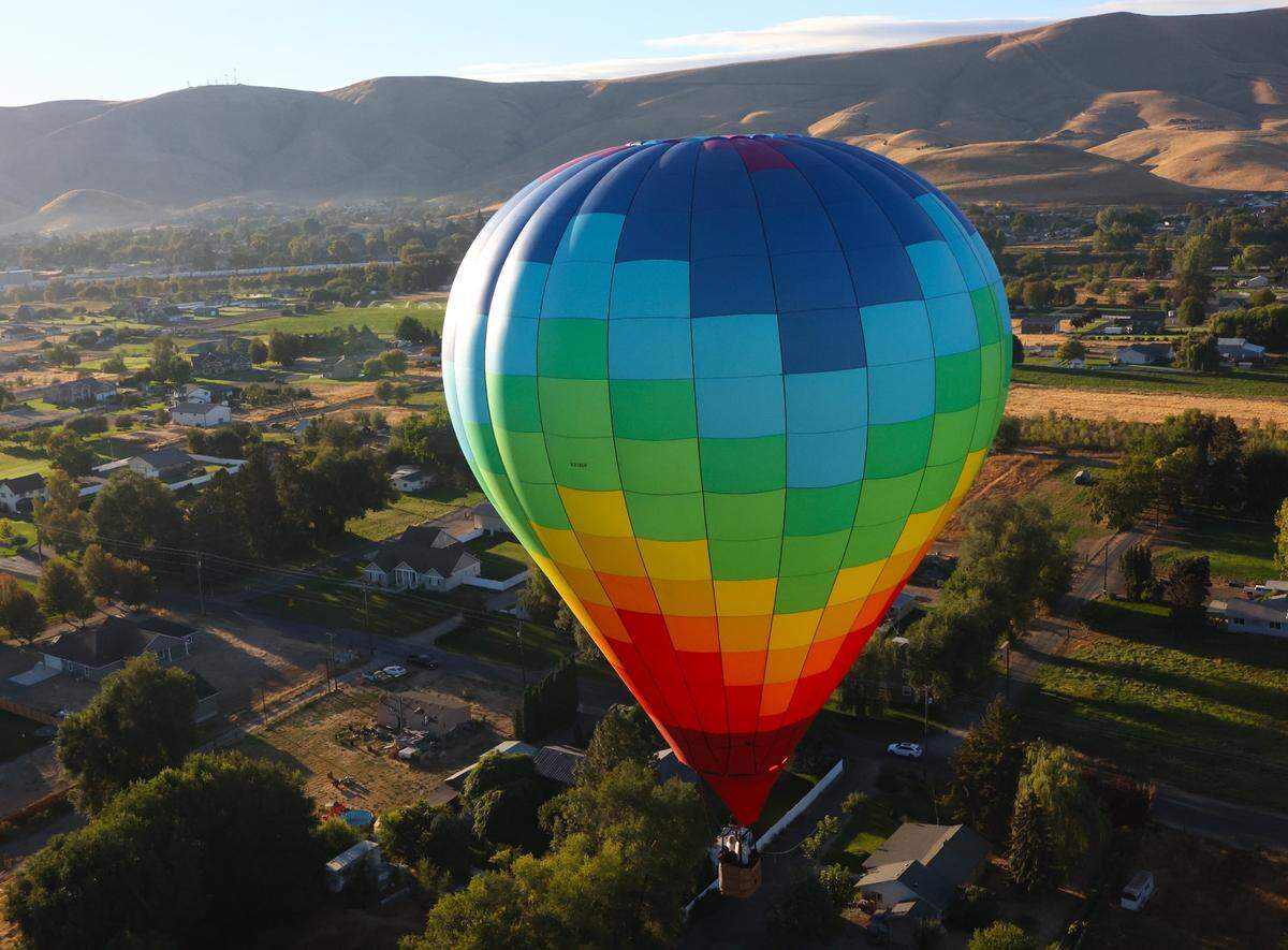 A rainbow-colored balloon flies low at the 2024 Great Prosser Balloon Rally.