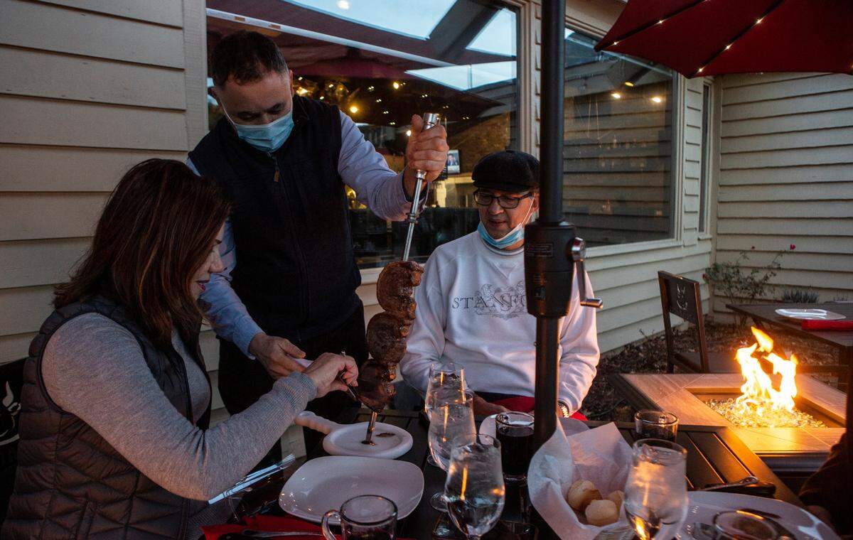 Boiada Brazilian Grill owner Josiane Ballin is served picanha, a sirloin cap steak cooked in the traditional Brazilian churrascaria-style, at her restaurant’s outdoor patio with fire pits and space heaters around the tables.
