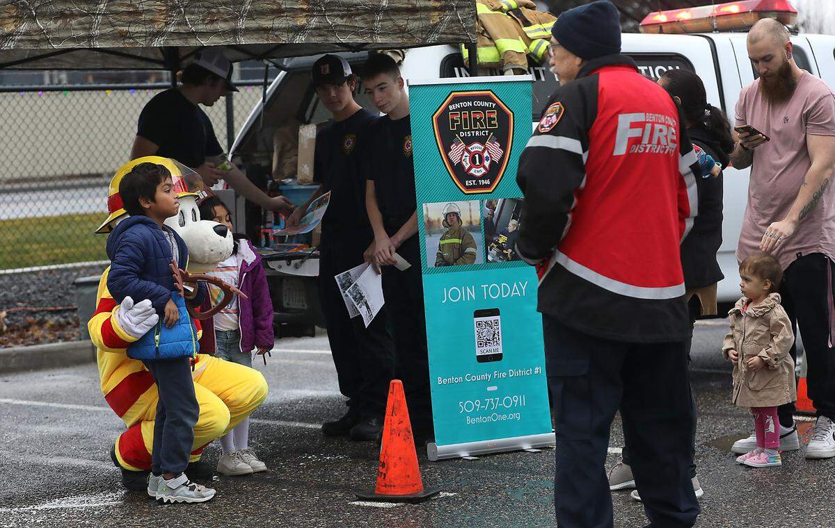 Children get their photo taken with Sparky the Fire Dog during Wednesday’s free Christmas event held at the Kennewick Irrigation District office on South Ely Street in Kennewick.