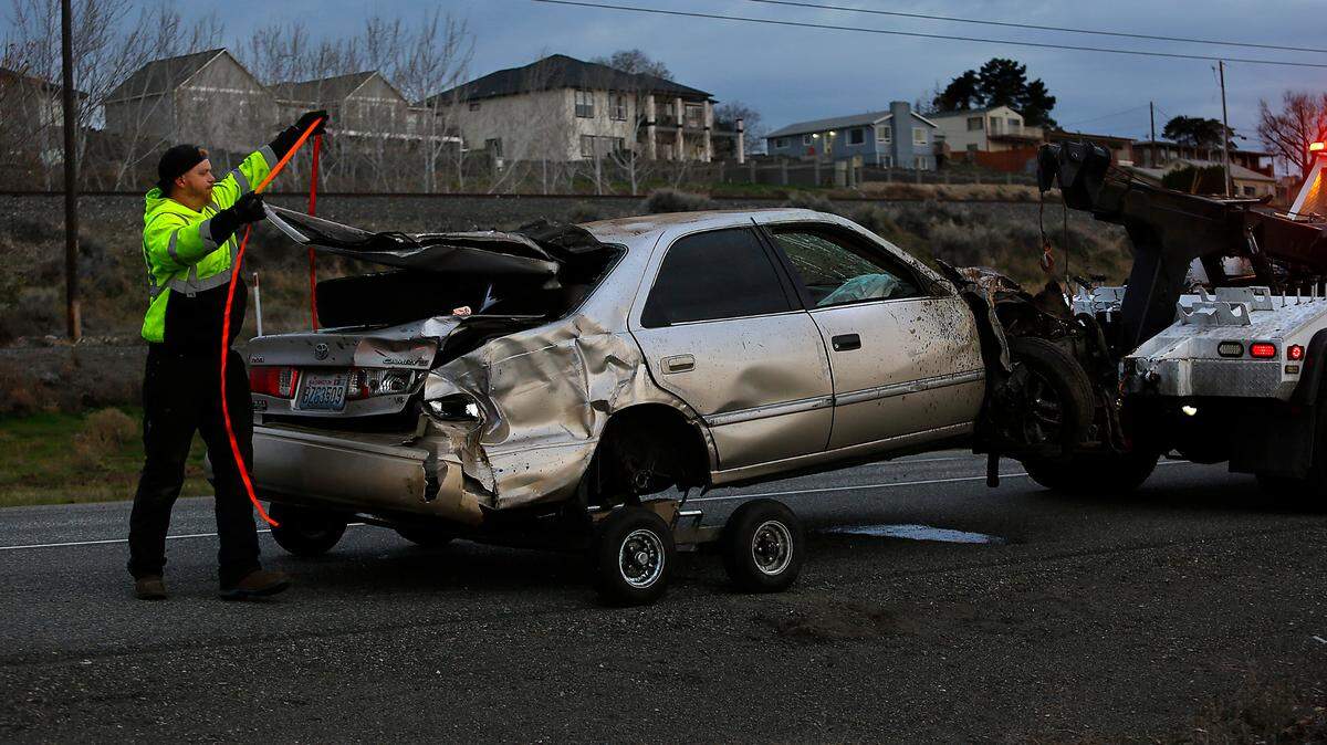 A tow truck driver from Clearwater Collision & Towing works to remove the heavily damaged Toyota Camry involved in Tuesday’s early fatal wreck on Highway 240.