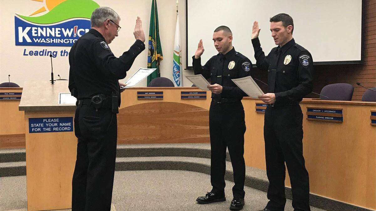 Kennewick police Chief Ken Hohenberg administers the oath to officers Sebastian Castilleja and Aaron Stites Friday morning.