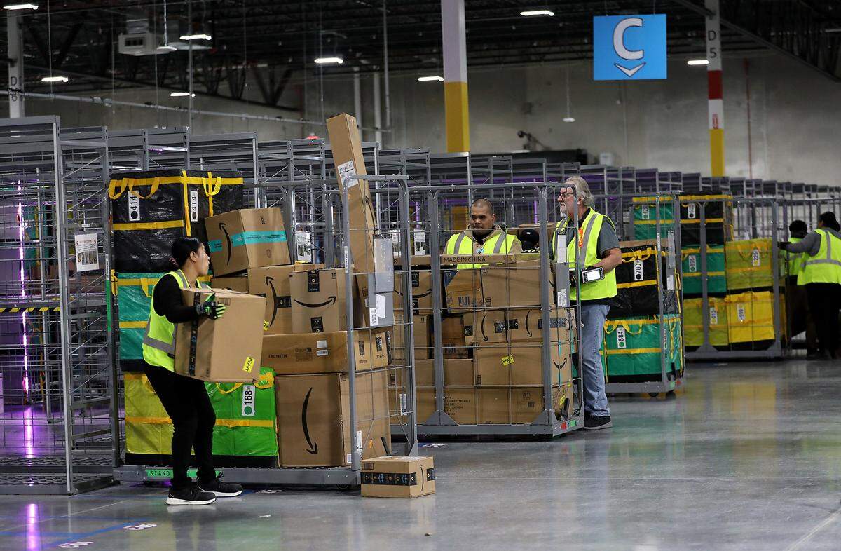 Employees at the new Amazon delivery station in Pasco sort packages onto rolling carts in preparation for delivery to the Tri-Cities area.