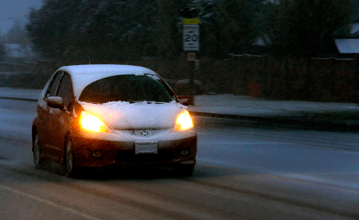 An early morning commuter in a snow covered car drives south on Union Street in Kennewick Monday morning as snow continues to fall and coat the Mid-Columbia during a spring snowstorm.