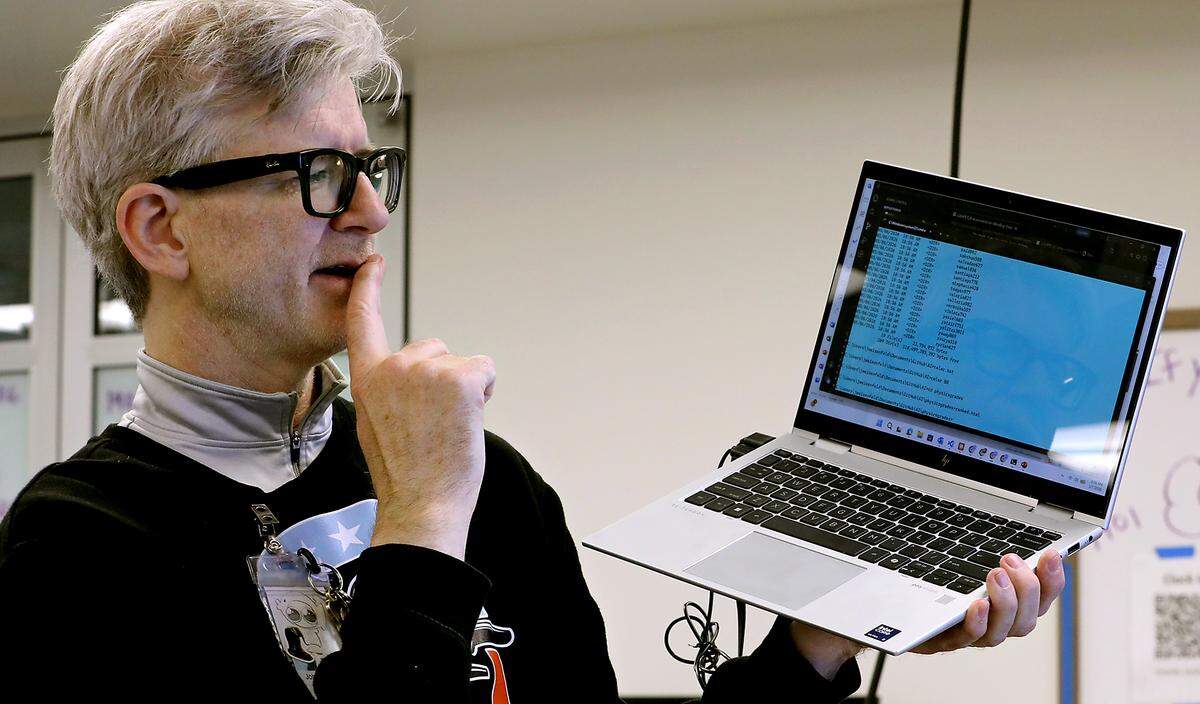 Orion High school John Weisenfeld holds his laptop while demonstrating the AI component students used to research their recent projects.