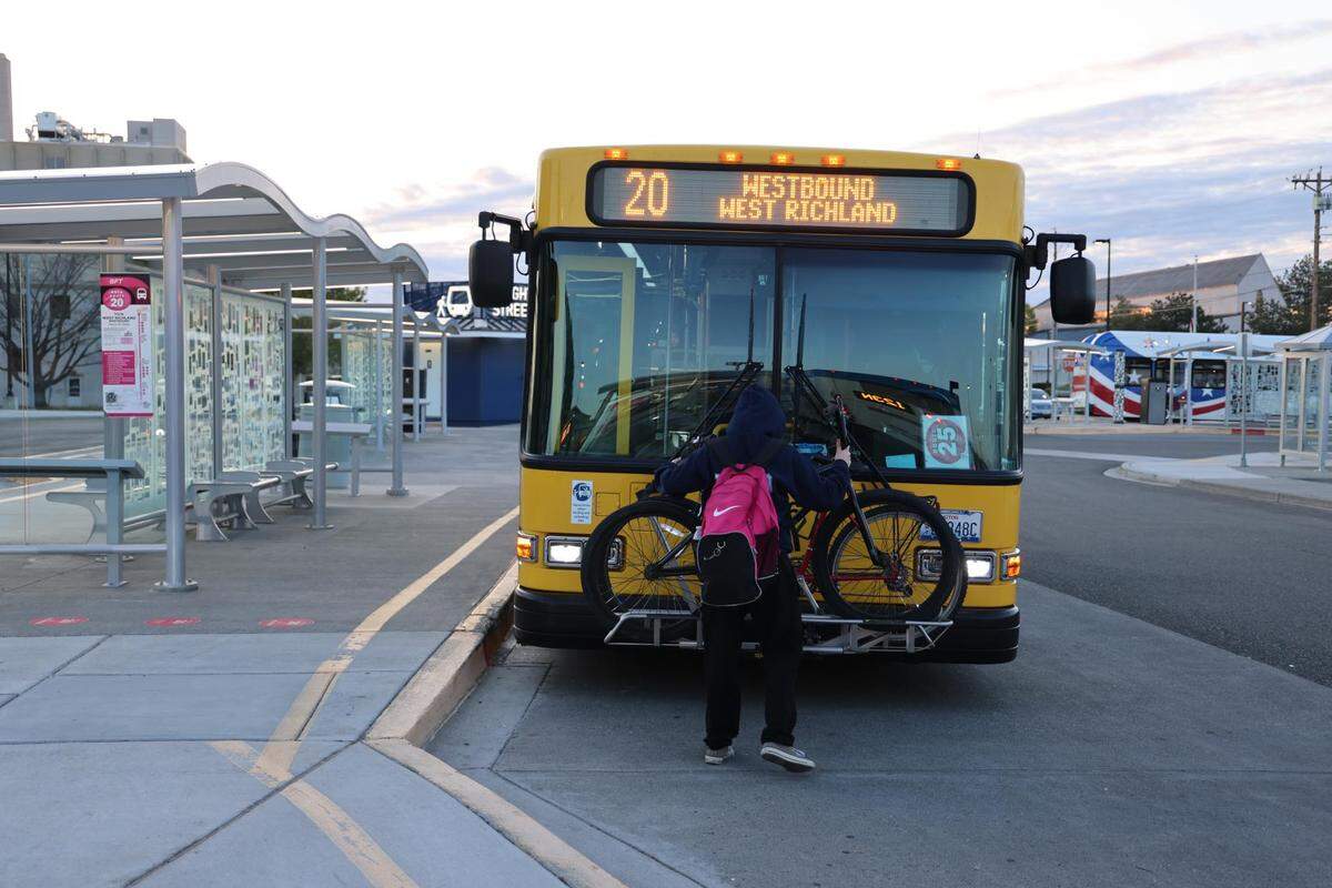 A passenger loading a bike onto a Ben Franklin Transit bus.