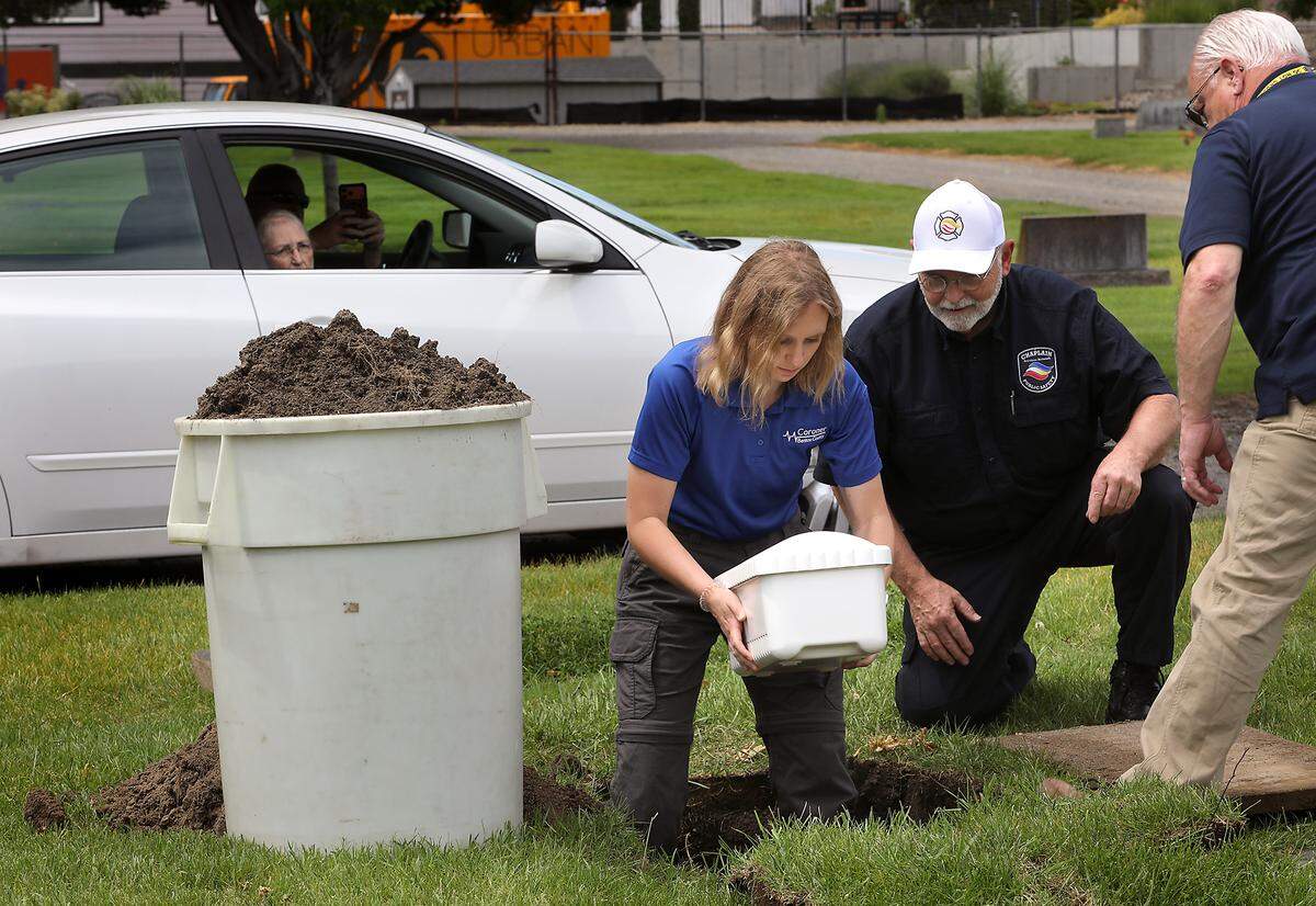 Benton County Coroner intern Salem Gray gently places Baby Doe in the ground with assistance from Chaplain Bill Lotz of Chaplain Services Network, middle, and Benton County Coroner Bill Leach during a reinterment ceremony at Richland’s Resthaven Cemetery. 