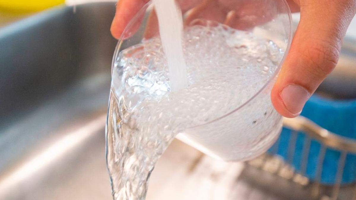 A person fills a plastic cup with tap water.