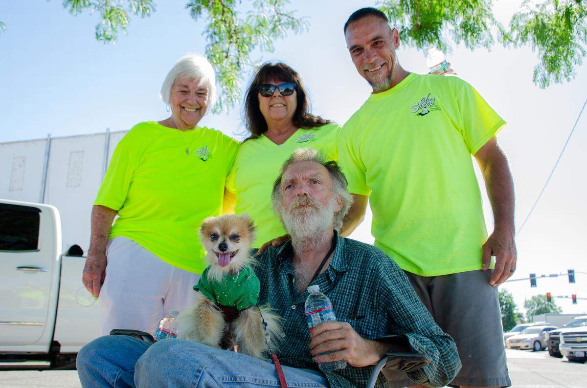 From left, Clean Sweep organization members Lynne “Mama Lynne” McKee, Jeannie Bender and Mark McKee crowd around felllow volunteer Doug Barnes on Friday after the group finished handing out chilled water bottles to homeless individuals downtown. The group is trying to get the city to loosen its restrictions after a complaint to the city of Pasco led to their organized events being restricted out of downtown.