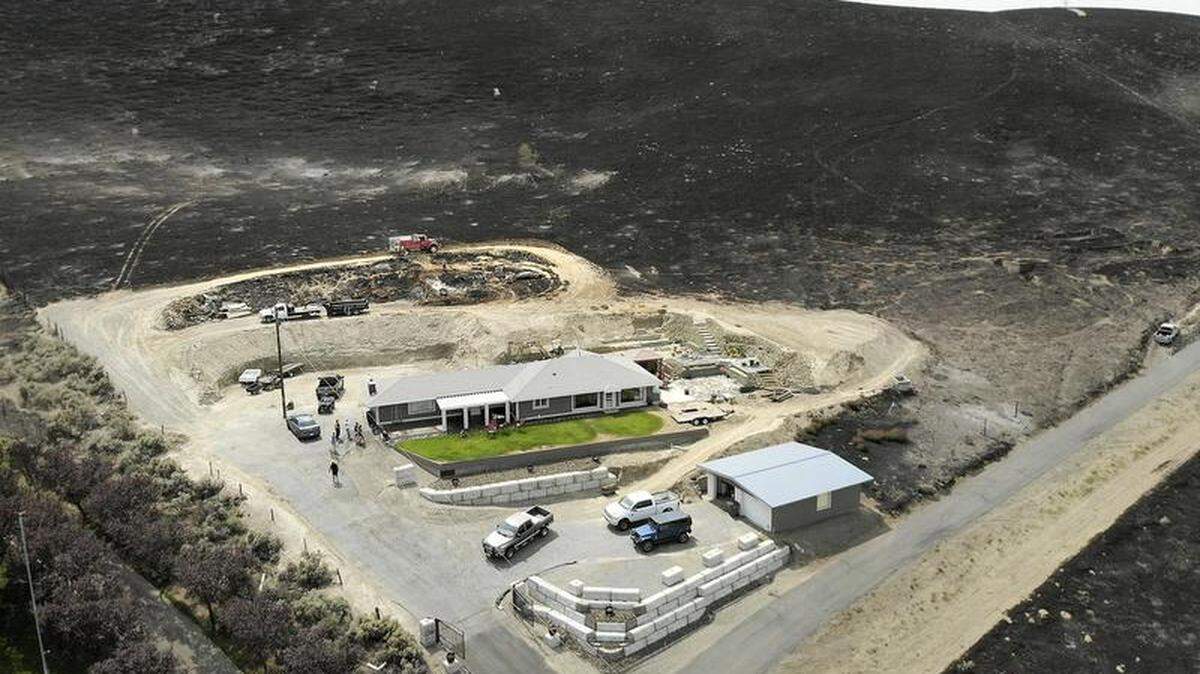 A fire truck monitors the charred landscape for hot spots Sunday afternoon behind a house at the end of South Ely Street in Kennewick. Fire officials say the 5,000-acre wildfire that roared into Kennewick and continued east into Benton County over the weekend is  now considered to be fully contained. 