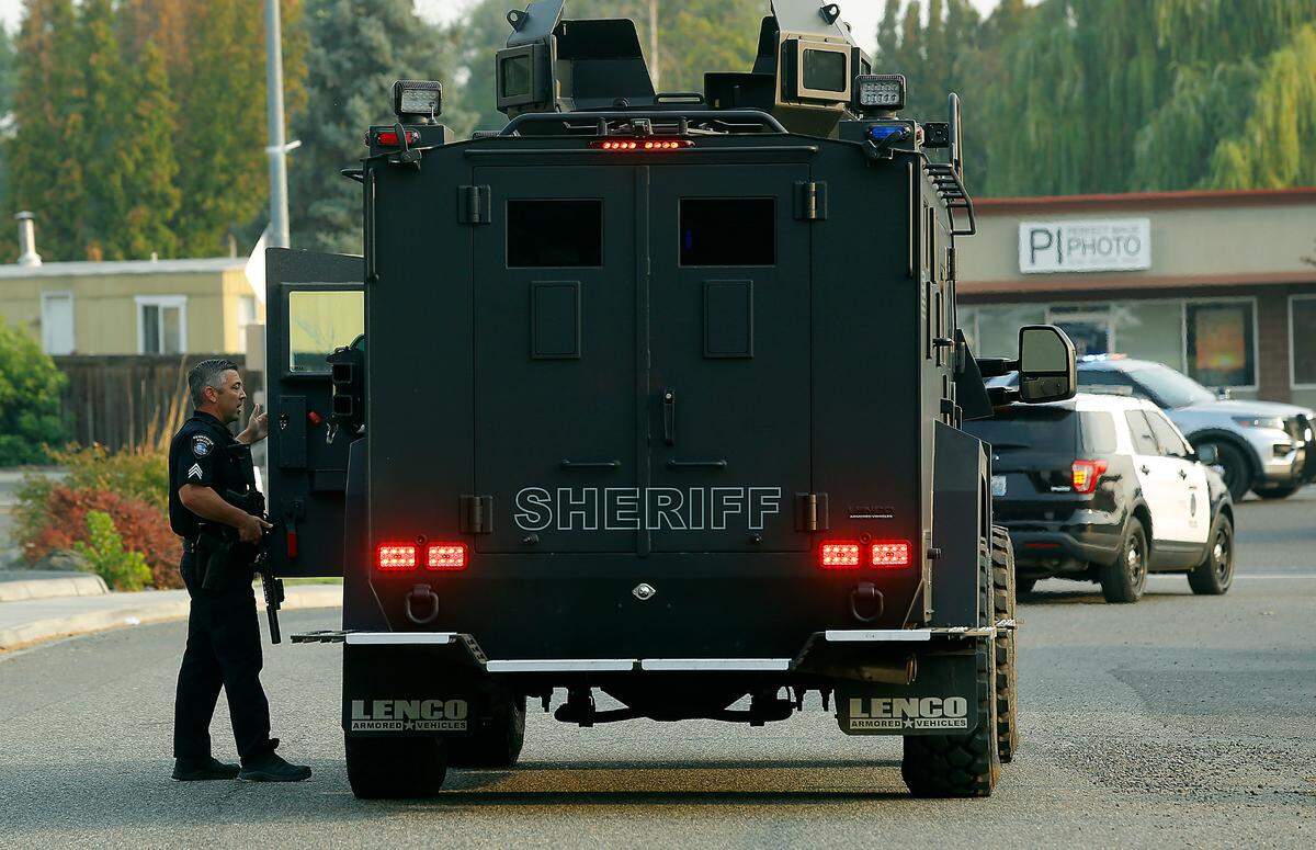 A Kennewick police officer provides information to the driver of the armored Tri-Cities Regional SWAT team on West Van Giesen Street at 41st Avenue following an officer-involved shooting on the busy road in August 2021.