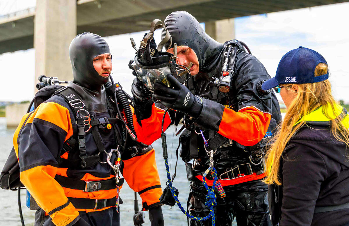 Columbia Basin Dive Rescue divers Cyrus Stanley, left, and Ben Prueitt inspect dive equipment while boat operator Jessie Bell prepares for another search Sunday on the Columbia River near the cable bridge.