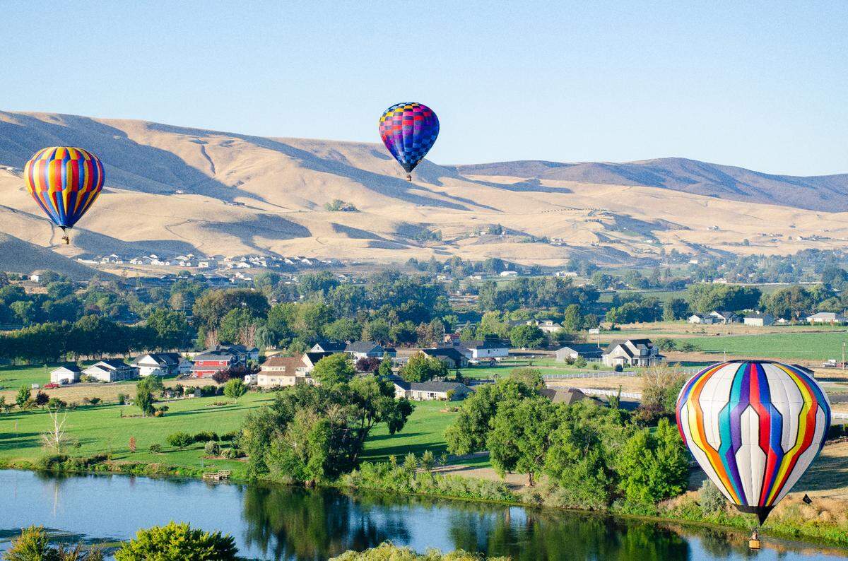 Hot air balloons hover over the Yakima River and city of Prosser early morning Friday during the start of the 33rd annual Great Prosser Balloon Rally.