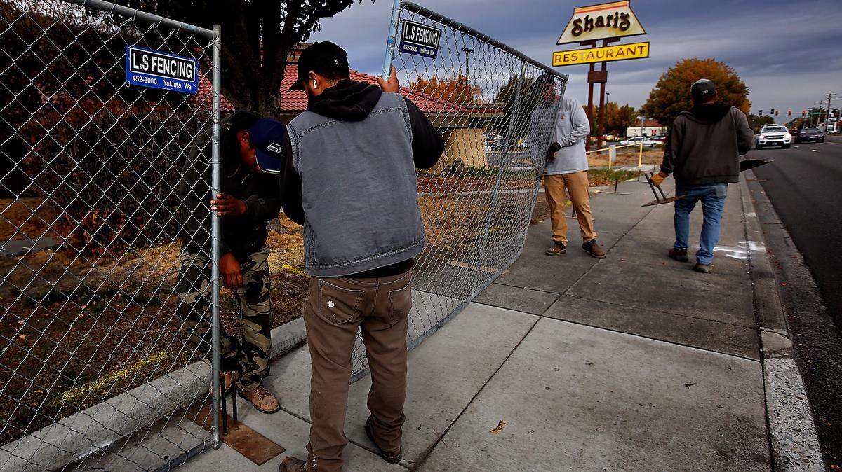 Workers install a temporary fence around the former Shari’s Restaurant near the Washington Plaza strip mall on George Washington Way in Richland. The building is being torn down.
