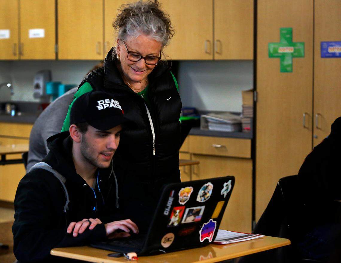 Special education paraeducator Nan Duncan helps Richland High student George Murray in this 2023 file photo. The Washington Legislature is considering pay increases for paraeducators statewide.