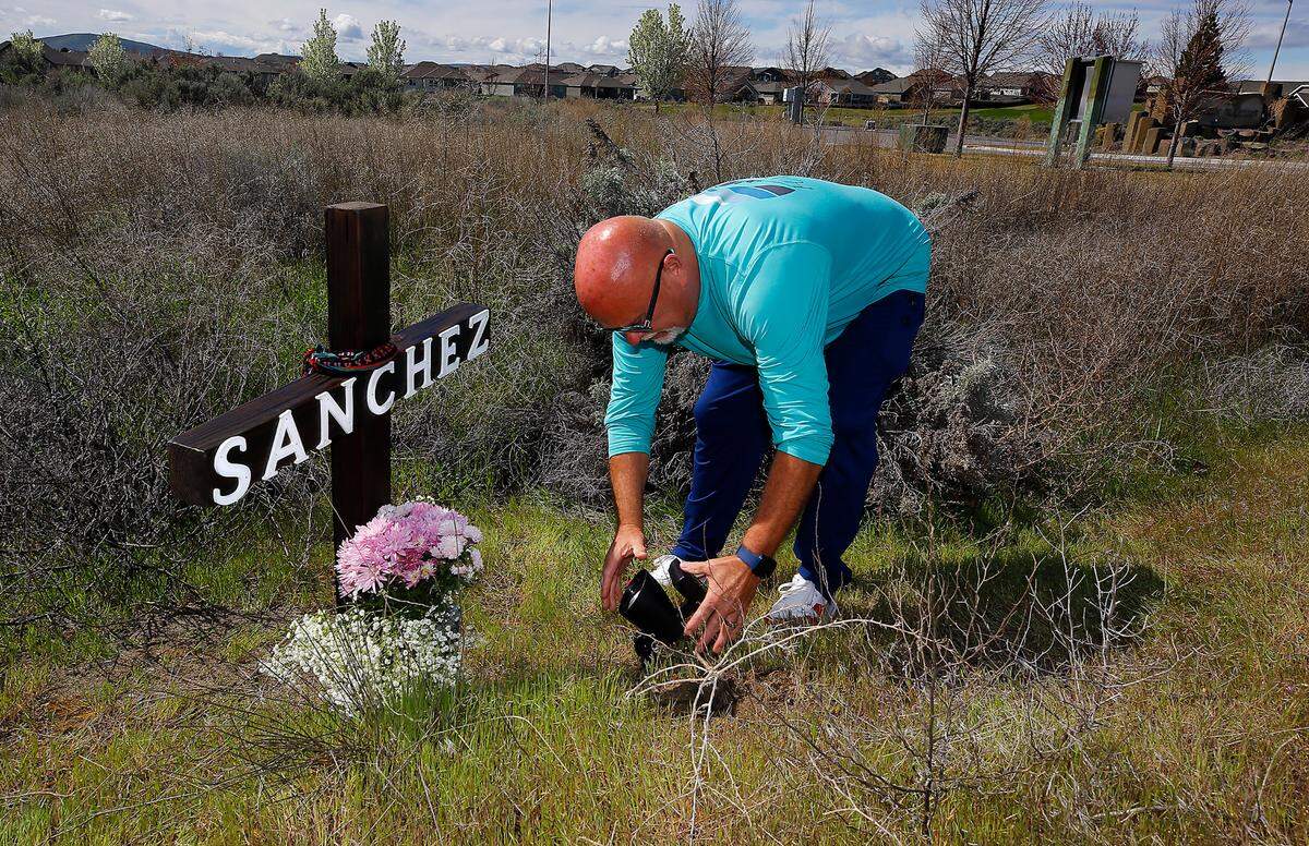 Ron Bouslaugh places a solar powered spotlight at a roadside memorial recently by family and community members off Highway 240 where Vega Sanchez was hit and killed on March 1. Bouslaugh lives in the Horn Rapids housing development where Sanchez and Trooper Sara Clasen both live.