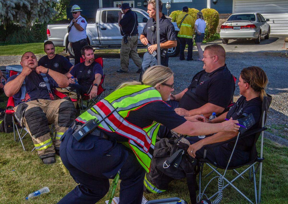Due to the extreme heat in the Tri-Cities, firefighters had to cool off, drink water and have their vitals taken after finishing one canister of compressed air while fighting a house fire in Pasco on Monday.