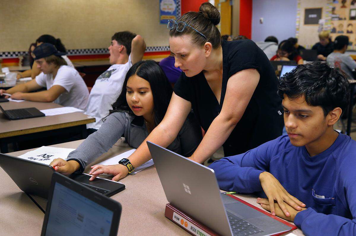 Teacher Ashley Rhoton helps students Alizandra Garcia, left, and Brandon Cedillo, both juniors, with their history classroom assingment recently at River View High School in Finley. Students, staff and parents are adjusting to a new four-day schedule.