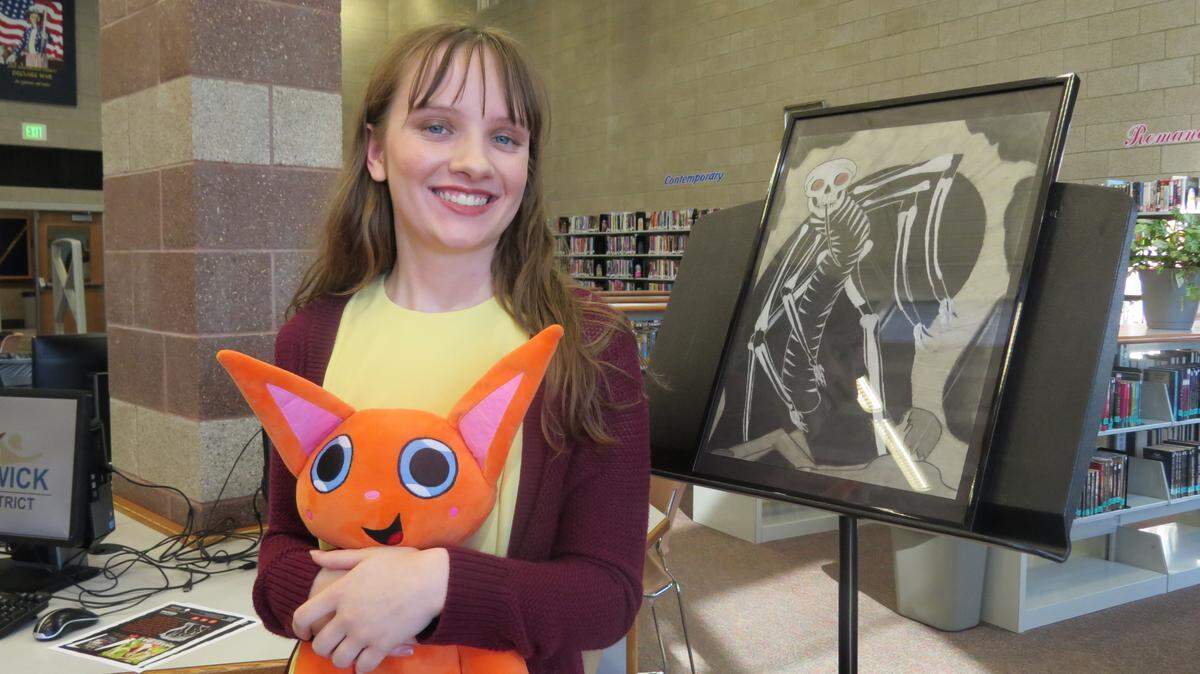 Bailey Simpson, 17, stands next to a painting of one of her characters and holding a stuffed animal of one of the others from her new book The Amazing Imagination Machine.