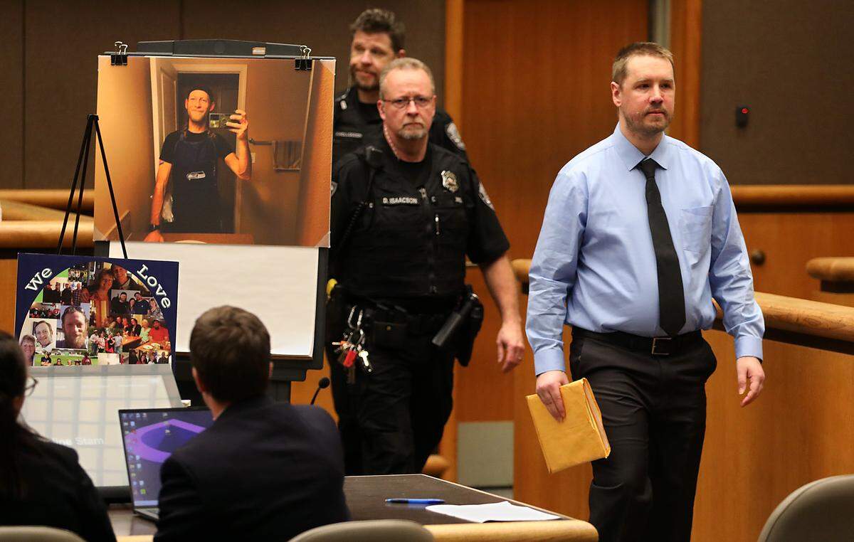 Richland Fred Meyer shooter Aaron Kelly walks past photos displayed of victim Justin Krumbah at the start of his Monday hearing in Benton County Superior Court.