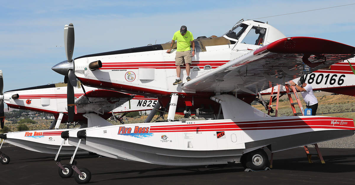Crew chiefs Hunter Phelps, left, and Nathan Pillsbury work on an Air Tractor single engine air tanker currently stationed during wildfire season at the Port of Benton's Richland Airport.