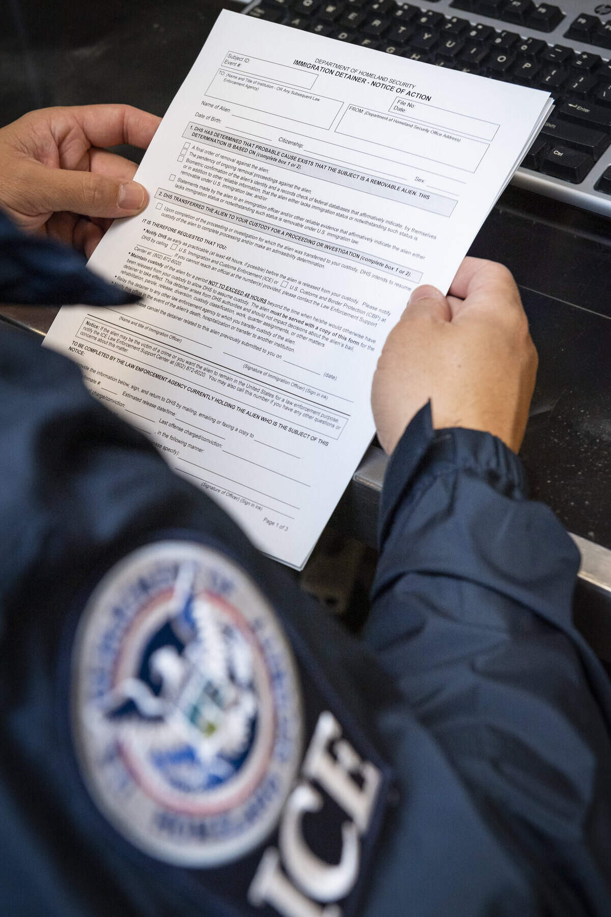 An Immigration and Customs Enforcement officer looks over paperwork