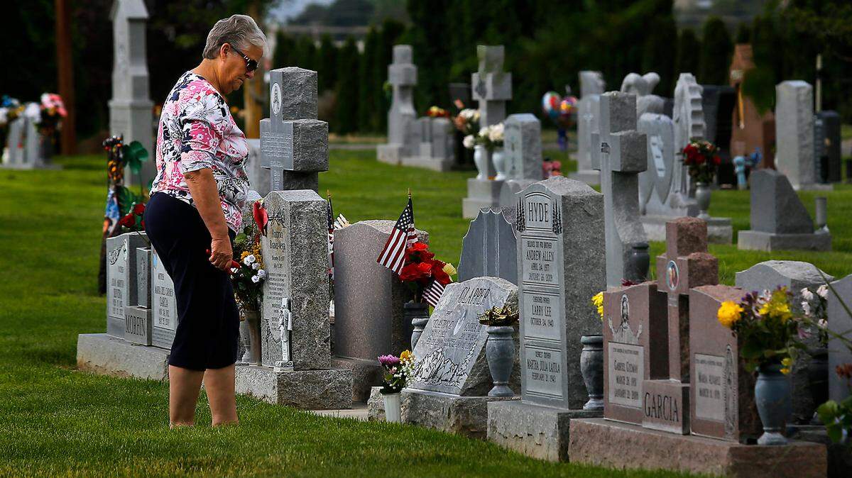 Susan Clapper pauses for a moment of quiet reflection after placing fresh flowers at the memorial markers for family members buried in the City View Cemetery at 1300 N. Oregon Ave. in Pasco. Cemeteries around the Mid-Columbia are decorated with flags and flowers to honor the Memorial Day holiday.